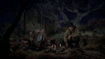 Movie still from “Gunfight at the O.K. Corral” (1957), directed by John Sturges – A group of men sitting around a fire at night; Wide shot, High angle