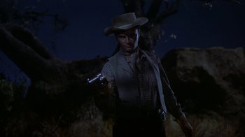 Movie still from “Gunfight at the O.K. Corral” (1957), directed by John Sturges – A man in a cowboy hat holding a gun in the dark; Medium shot, Low angle