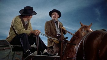 Movie still from “Gunfight at the O.K. Corral” (1957), directed by John Sturges – Two men sitting on a horse drawn carriage; Medium shot, Low angle