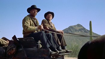 Movie still from “Gunfight at the O.K. Corral” (1957), directed by John Sturges – A couple of men sitting on top of a wagon; Medium shot, Low angle