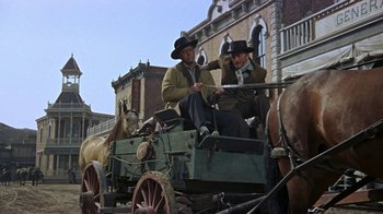 Movie still from “Gunfight at the O.K. Corral” (1957), directed by John Sturges – Two men riding in the back of a horse drawn carriage; Wide shot, Low angle