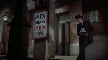 Movie still from “Gunfight at the O.K. Corral” (1957), directed by John Sturges – A man standing in front of a building next to a sign; Wide shot, Low angle
