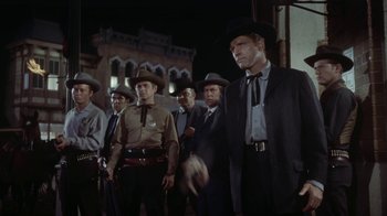 Movie still from “Gunfight at the O.K. Corral” (1957), directed by John Sturges – A group of men standing next to each other in suits; Medium shot, Low angle