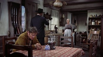 Movie still from “Gunfight at the O.K. Corral” (1957), directed by John Sturges – A group of people standing around a table in a room; Wide shot, Over the shoulder angle
