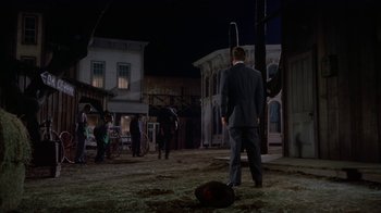 Movie still from “Gunfight at the O.K. Corral” (1957), directed by John Sturges – A man in a business suit standing in the middle of an empty street; Wide shot, Low angle