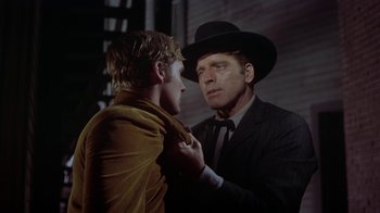Movie still from “Gunfight at the O.K. Corral” (1957), directed by John Sturges – A man in a suit and a cowboy hat touching another man in a suit; Close Up shot, Over the shoulder angle