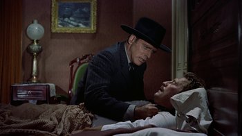 Movie still from “Gunfight at the O.K. Corral” (1957), directed by John Sturges – A man wearing a black hat is looking at another man's face; Medium shot, Over the shoulder angle