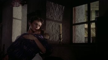 Movie still from “Gunfight at the O.K. Corral” (1957), directed by John Sturges – A woman holding a child in a room with a window; Medium shot, Low angle