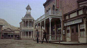 Movie still from “Gunfight at the O.K. Corral” (1957), directed by John Sturges – Two men walking down the street in front of some buildings; Wide shot, Low angle