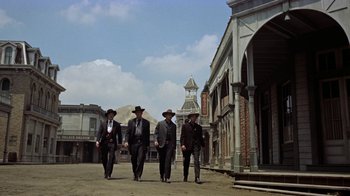 Movie still from “Gunfight at the O.K. Corral” (1957), directed by John Sturges – A group of men walking down a street in suits; Wide shot, Low angle