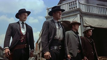 Movie still from “Gunfight at the O.K. Corral” (1957), directed by John Sturges – A group of men in suits and hats walking down a street; Medium shot, Low angle