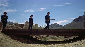 Movie still from “Gunfight at the O.K. Corral” (1957), directed by John Sturges – A couple of men walking across a wooden bridge; Wide shot, Low angle