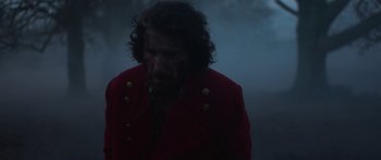Movie still from “Gwen” (2018), directed by William McGregor – A man in a red jacket standing in the fog; Medium shot, Over the shoulder angle