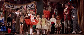 Movie still from “Gypsy” (1962), directed by Mervyn LeRoy – A group of people standing on a stage with costumes on; Wide shot, Low angle