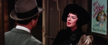 Movie still from “Gypsy” (1962), directed by Mervyn LeRoy – A woman wearing a black hat and a black coat talking to a man in a black hat; Close Up shot, Over the shoulder angle