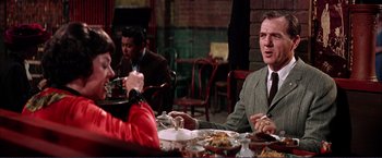 Movie still from “Gypsy” (1962), directed by Mervyn LeRoy – A group of people sitting at a table with plates of food on it; Medium shot, Over the shoulder angle
