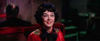 Movie still from “Gypsy” (1962), directed by Mervyn LeRoy – An older woman in a red jacket and black bow tie; Close Up shot, Low angle