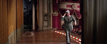 Movie still from “Gypsy” (1962), directed by Mervyn LeRoy – A man in a gray suit and a hat on a stage; Wide shot, Low angle