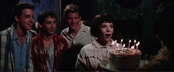 Movie still from “Gypsy” (1962), directed by Mervyn LeRoy – A group of people standing next to a cake; Medium shot, Over the shoulder angle