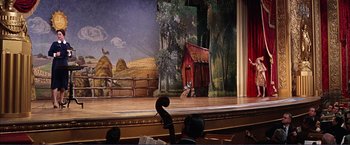 Movie still from “Gypsy” (1962), directed by Mervyn LeRoy – The stage of a theater with a violin and a painting of a barn; Wide shot, Low angle
