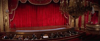 Movie still from “Gypsy” (1962), directed by Mervyn LeRoy – A group of people sitting on a stage in front of a red curtain; Extreme Wide shot, High angle