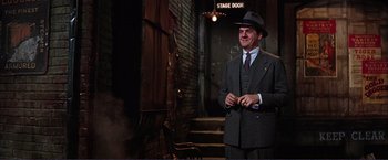 Movie still from “Gypsy” (1962), directed by Mervyn LeRoy – A man in a suit and hat standing in front of a stage door; Medium shot, Low angle
