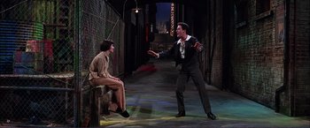 Movie still from “Gypsy” (1962), directed by Mervyn LeRoy – A man in a suit and tie talking to a woman in a brown dress; Wide shot, Low angle