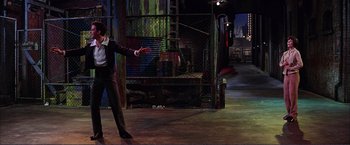 Movie still from “Gypsy” (1962), directed by Mervyn LeRoy – A man in a suit and tie throwing a frisbee; Wide shot, Low angle