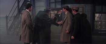 Movie still from “Gypsy” (1962), directed by Mervyn LeRoy – A group of men standing next to each other in a room; Medium shot, Over the shoulder angle