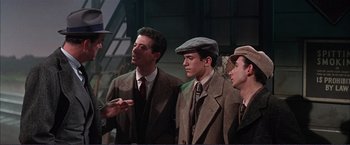 Movie still from “Gypsy” (1962), directed by Mervyn LeRoy – A group of men standing next to each other wearing suits; Medium shot, Over the shoulder angle