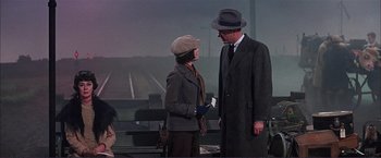 Movie still from “Gypsy” (1962), directed by Mervyn LeRoy – A man and a woman standing next to each other in front of train tracks; Medium shot, Over the shoulder angle