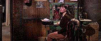 Movie still from “Gypsy” (1962), directed by Mervyn LeRoy – A woman sitting at a desk in a room; Medium shot, Over the shoulder angle