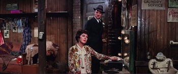 Movie still from “Gypsy” (1962), directed by Mervyn LeRoy – A woman and a man standing next to each other in a room; Medium shot, Over the shoulder angle