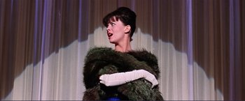 Movie still from “Gypsy” (1962), directed by Mervyn LeRoy – A woman in a green fur coat and a white glove; Medium shot, Low angle