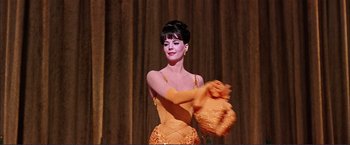 Movie still from “Gypsy” (1962), directed by Mervyn LeRoy – A beautiful woman in a yellow dress holding a bag; Medium shot, Low angle