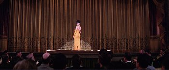 Movie still from “Gypsy” (1962), directed by Mervyn LeRoy – A woman standing on a stage wearing a yellow dress; Wide shot, Low angle