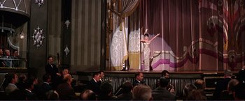 Movie still from “Gypsy” (1962), directed by Mervyn LeRoy – A woman in a dress on a stage with people; Extreme Wide shot, Low angle