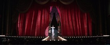 Movie still from “Gypsy” (1962), directed by Mervyn LeRoy – A woman standing on a stage in front of a red curtain; Extreme Wide shot, Low angle