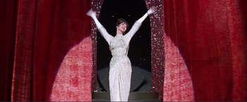 Movie still from “Gypsy” (1962), directed by Mervyn LeRoy – A woman in a white dress is standing on a stage; Medium shot, Low angle