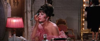 Movie still from “Gypsy” (1962), directed by Mervyn LeRoy – A woman in a pink dress putting makeup on her face; Close Up shot, Over the shoulder angle
