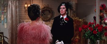 Movie still from “Gypsy” (1962), directed by Mervyn LeRoy – A man in a black suit and a woman in a pink dress; Medium shot, Over the shoulder angle