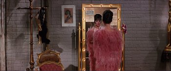 Movie still from “Gypsy” (1962), directed by Mervyn LeRoy – A woman in a pink dress looking in a mirror; Medium shot, Over the shoulder angle