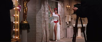 Movie still from “Gypsy” (1962), directed by Mervyn LeRoy – A woman in a white dress and a red hat; Wide shot, Low angle