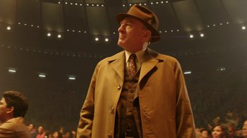 Movie still from “Hands of Stone” (2016), directed by Jonathan Jakubowicz – An older man wearing a hat and a brown coat; Medium shot, Low angle