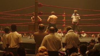 Movie still from “Hands of Stone” (2016), directed by Jonathan Jakubowicz – A group of people in a boxing ring watching a match; Extreme Wide shot, High angle