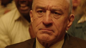 Movie still from “Hands of Stone” (2016), directed by Jonathan Jakubowicz – An older man in a suit and tie looking angry; Close Up shot, Over the shoulder angle