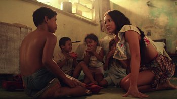 Movie still from “Hands of Stone” (2016), directed by Jonathan Jakubowicz – A group of people sitting on the floor eating food; Medium shot, Low angle