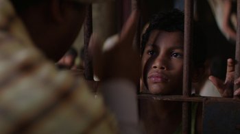 Movie still from “Hands of Stone” (2016), directed by Jonathan Jakubowicz – A young boy is looking through the bars of a jail cell; Close Up shot, Over the shoulder angle