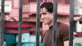 Movie still from “Hands of Stone” (2016), directed by Jonathan Jakubowicz – A young man standing behind a fence looking at the camera; Close Up shot, Over the shoulder angle