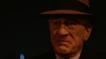 Movie still from “Hands of Stone” (2016), directed by Jonathan Jakubowicz – An older man wearing a hat and a suit; Close Up shot, Over the shoulder angle